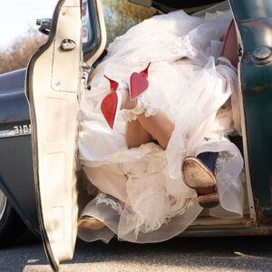 A bride with her feet out of an old truck